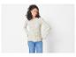 Une femme portant un pull crème et un jean bleu.