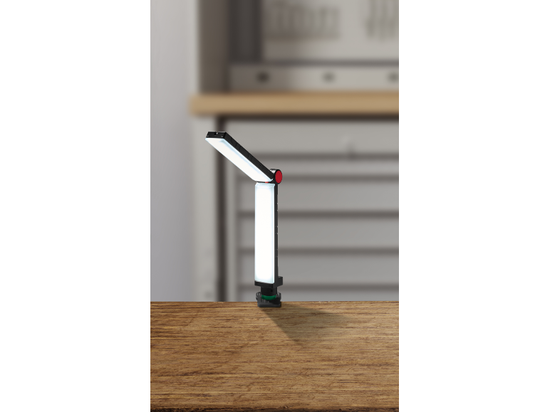 Lampe de travail LED réglable avec pince sur une surface en bois dans un atelier.
