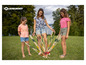 Trois filles jouent à un jeu avec de longs bâtons en bois sur l'herbe.