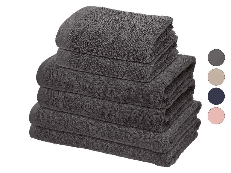 Pile de serviettes gris foncé avec échantillons de couleurs pour gris, beige, bleu marine et rose.