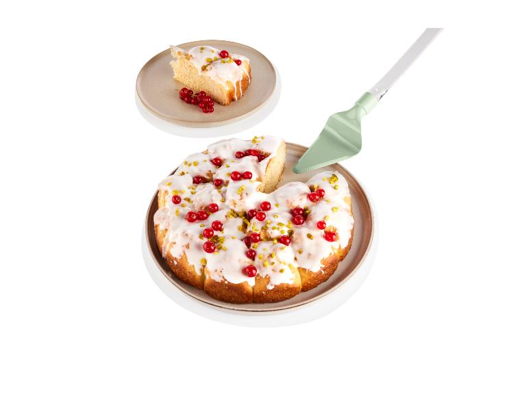 Un gâteau glacé aux baies rouges et une spatule de service.