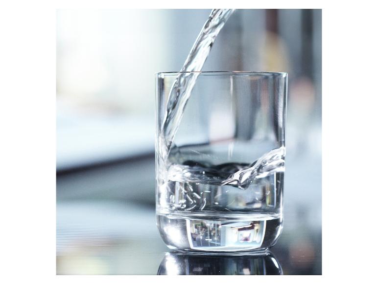 De l'eau versée dans un verre, reflétant l'environnement.