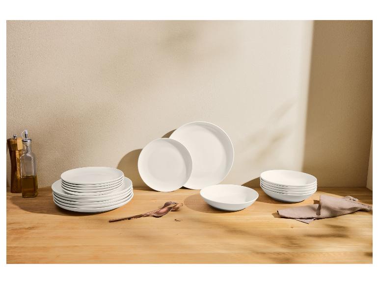 Ensemble de vaisselle blanche sur une table en bois, avec des bouteilles d'huile et d'épices.