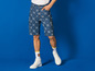 Un homme portant un short en jean bleu avec le logo Lidl et des baskets blanches.