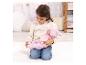 Une jeune fille en sweat à capuche et jean agenouillée sur un tapis, tenant une poupée bébé en tenue rose.