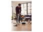 Un homme aspire le sol avec un aspirateur.