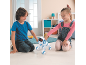 Deux enfants jouent avec un chiot robot blanc et bleu sur le sol.