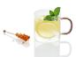 Un verre de thé au citron et à la menthe et une baguette de sucre cristallisé.