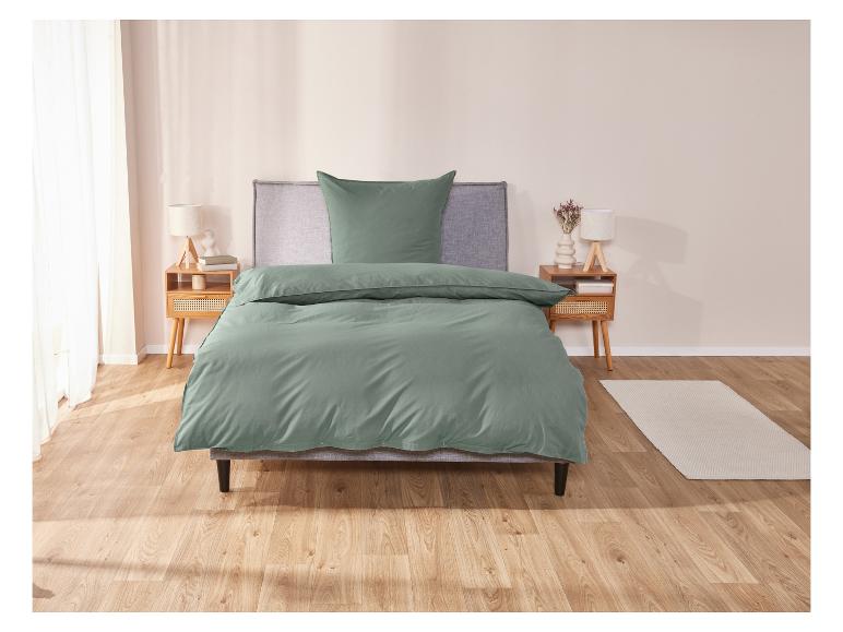 Une housse de couette verte sur un lit avec deux tables de chevet.