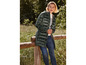 Une femme porte une veste en duvet verte et un jean en plein air.