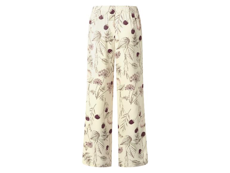 Pantalon large à motif floral et de baies sur fond crème.
