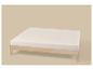 Cadre de lit en bois clair avec matelas blanc sur fond beige.