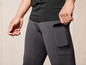 Un homme porte un pantalon de jogging noir avec un téléphone dans la poche.