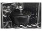 Marmite noire en fonte avec couvercle à l'intérieur d'un four sur une grille métallique