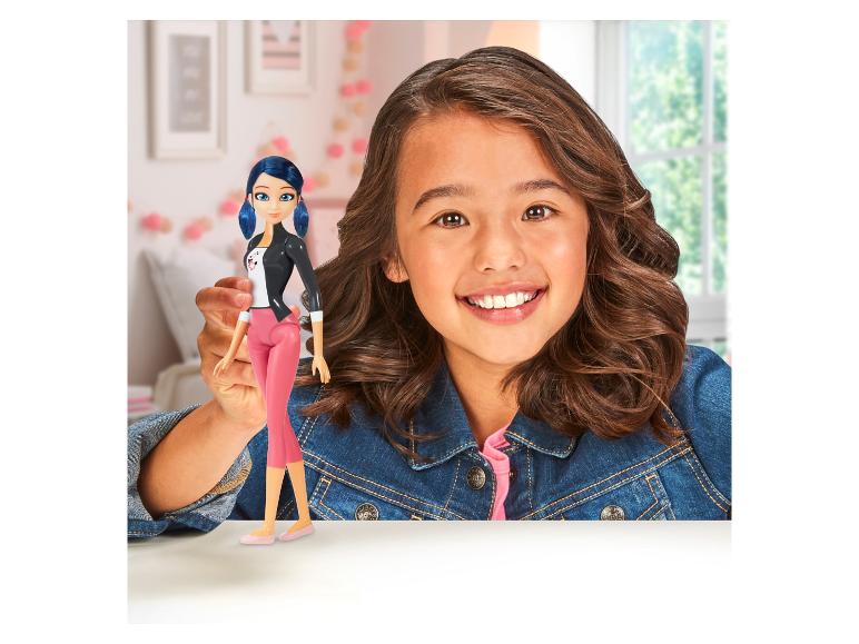 Une fille tient une poupée Ladybug.