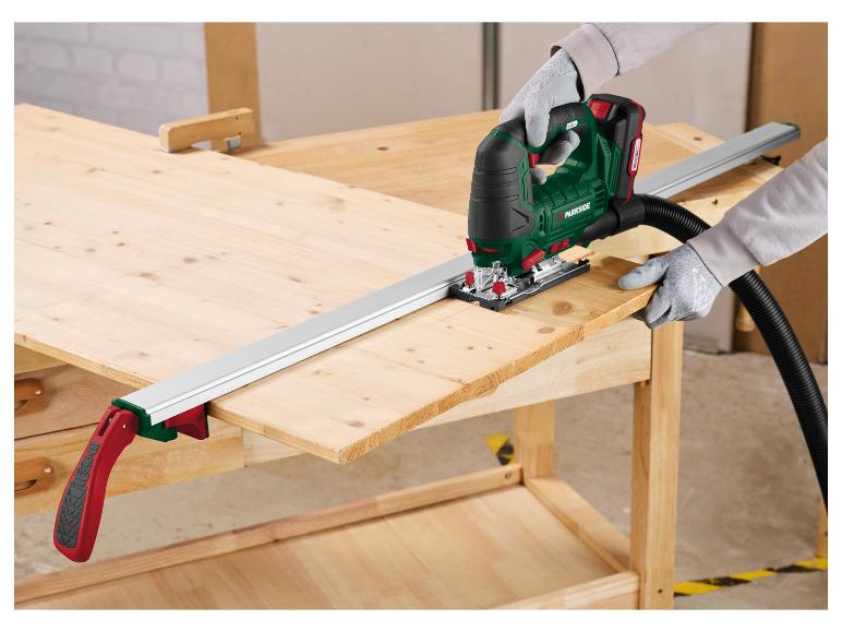 Personne coupant du bois avec une scie sauteuse Parkside et un guide de coupe sur un établi.