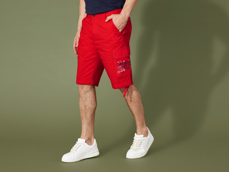 Homme portant un short cargo rouge avec le logo 'Miss Nature Company' et des baskets blanches.