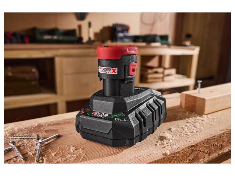 Batterie PARKSIDE® 12 V / 2 Ah et chargeur 2,4 A sur une table en bois avec des vis.