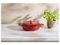 Cocotte en fonte rouge sur un comptoir en marbre blanc avec un plant de basilic.