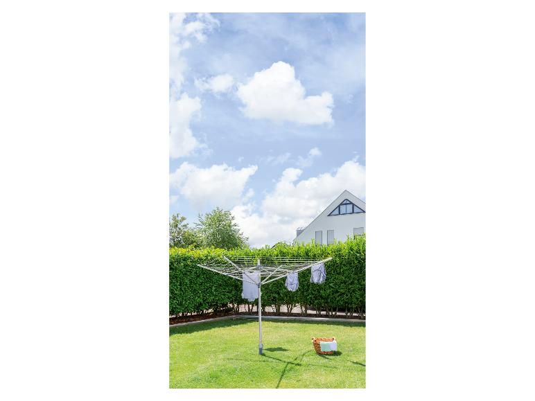 Un étendoir à linge rotatif avec du linge qui sèche dans un jardin ensoleillé.