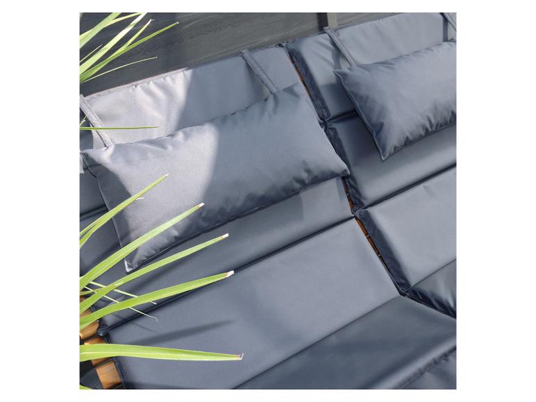 Coussins et matelas de jardin gris avec plantes vertes.