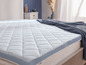 Une couette blanche avec un bord bleu sur un lit.