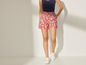 Femme portant un short rouge à motif blanc et des baskets blanches.