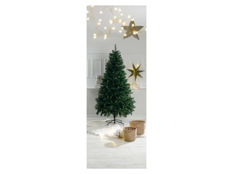 Sapin de Noël avec guirlandes lumineuses et paniers tressés sur un sol en bois blanc.