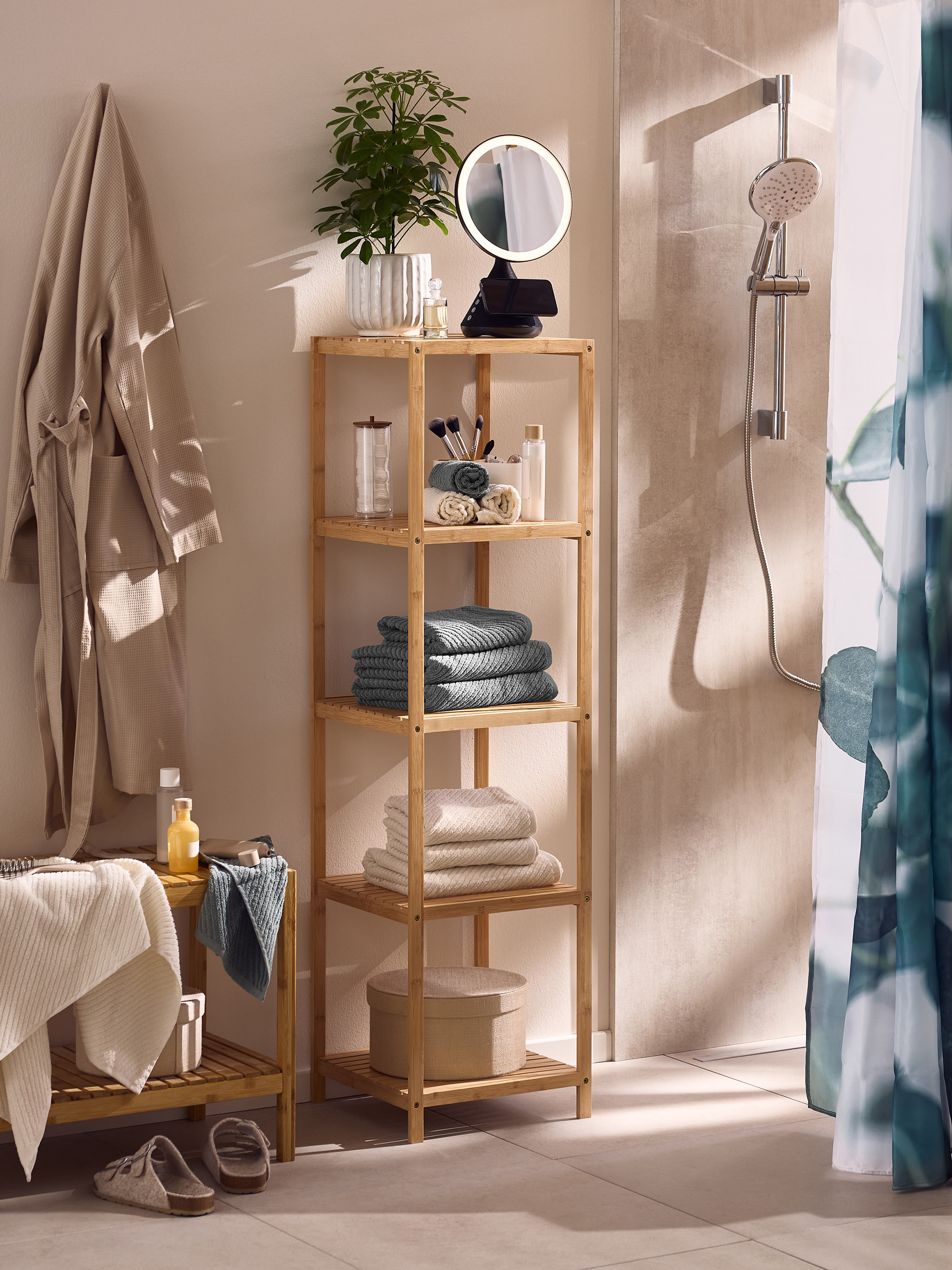 Salle de bain avec étagère en bambou, peignoirs, serviettes et douche.