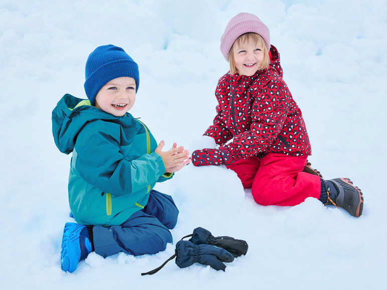 Deux enfants en vêtements d'hiver jouent dans la neige.