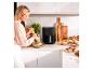 Une femme dans la cuisine avec une friteuse à air Eco+ de Cuisinart