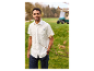 Un homme souriant portant une chemise blanche Lyle & Scott et un short bleu marine sur un terrain de golf.