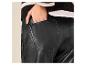 Gros plan d'une personne portant un pantalon en similicuir noir et un pull rayé.