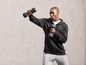 Un homme en sweat-shirt noir et pantalon gris, fait des exercices avec des haltères.