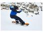 Garçon en snowboard avec casque et lunettes de ski sur une pente enneigée.