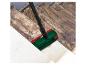 Une brosse verte avec des accents rouges nettoie un escalier en pierre sale.