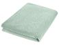 Couverture pliée vert clair, douce et moelleuse.