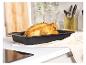 Un poulet rôti dans un plat à four noir sur un comptoir blanc.