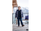 Petit garçon en veste d'hiver, pull, jean et bottes sur une terrasse enneigée.