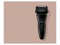 Rasoir électrique noir sur fond rose-beige.