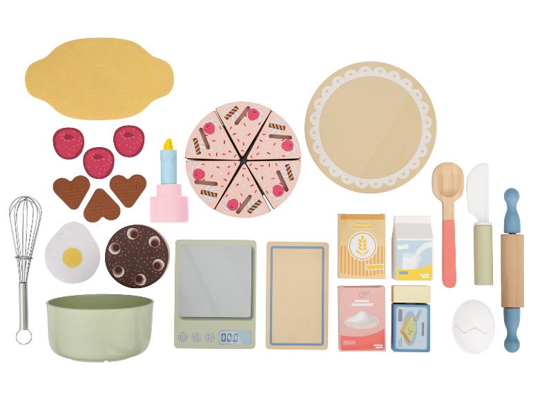 Un ensemble de jeu de pâtisserie avec un gâteau, des framboises, des ingrédients et des ustensiles.