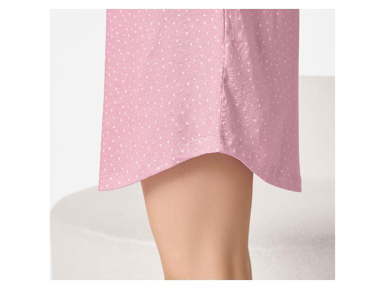 Gros plan de l'ourlet d'une chemise de nuit rose à pois avec une jambe visible.