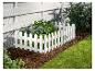 Clôture blanche avec des plantes dans un jardin.