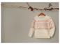 Un pull blanc avec un motif de Noël rose et doré.