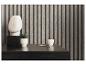 Commode noire avec vase blanc, plante et tasse devant un revêtement mural en bois.