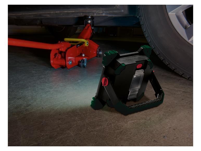 Lampe de travail LED éclairant une voiture soulevée et un cric hydraulique.
