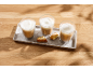 Trois verres de café au lait et biscuits sur un plateau en béton.