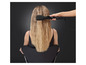 Une femme aux cheveux longs et blonds se fait appliquer un fer à friser Diva.