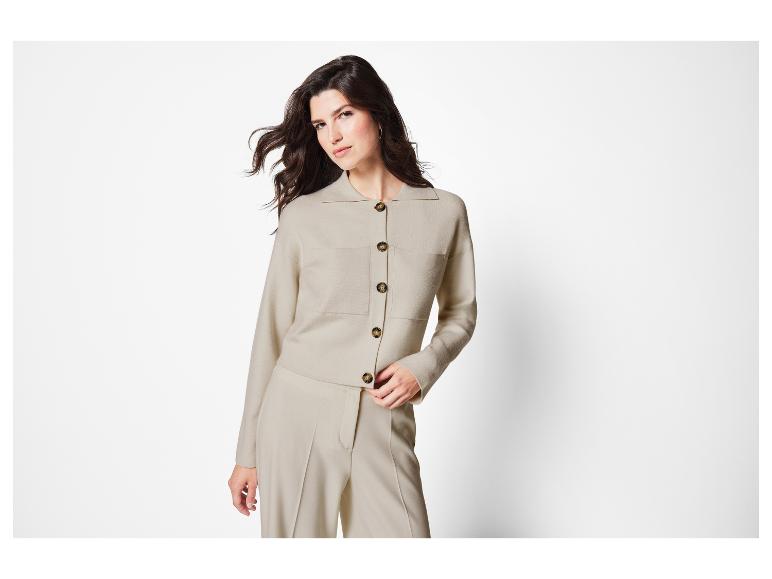 Une femme porte un pull beige et un pantalon.