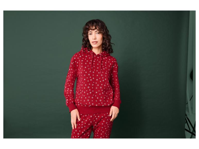 Femme portant un sweat-shirt rouge et un pantalon de jogging à motifs de flocons de neige.